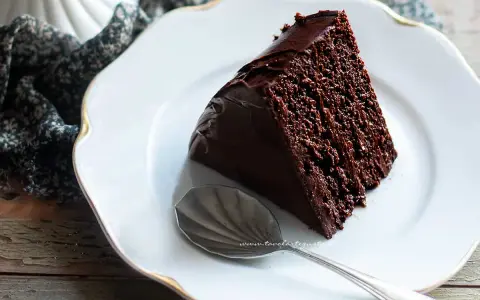 Una fetta di ciambellone al cioccolato, soffice e golosa, su un piatto bianco con un cucchiaino d'argento.