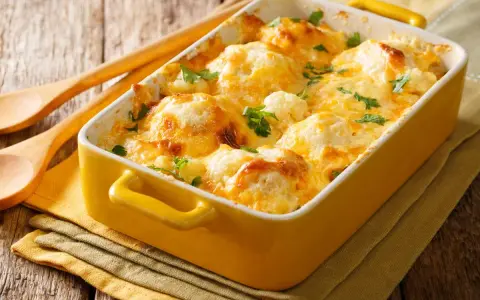 Cavolfiore al forno con pangrattato e formaggio filante, guarnito con prezzemolo fresco. Un piatto invitante e saporito.
