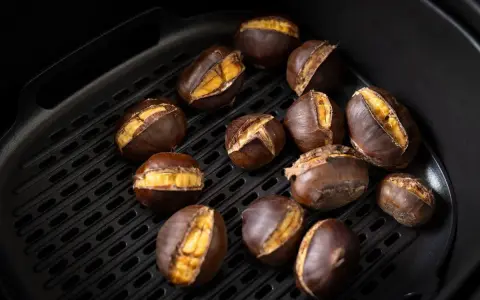 Castagne arrostite nella friggitrice ad aria, con la buccia aperta che rivela il loro interno dorato e invitante.