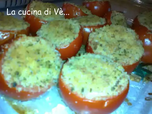 Pomodori gratinati al forno, ripieni di pangrattato e erbe aromatiche, pronti per essere gustati.