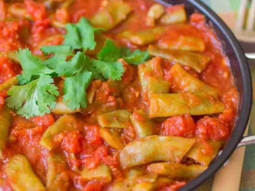 Taccole al pomodoro cotte in padella, guarnite con prezzemolo fresco. Un piatto semplice e gustoso.