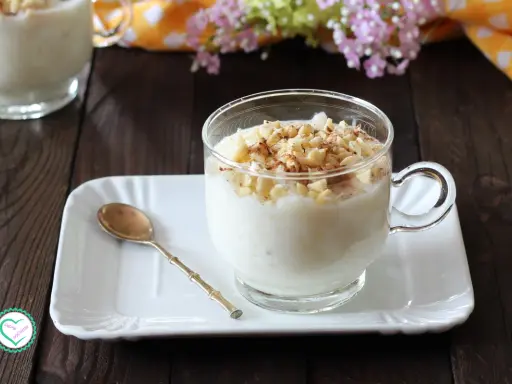 Una tazza di cremosa crema di riso, guarnita con mandorle tritate e cannella, pronta per essere gustata.