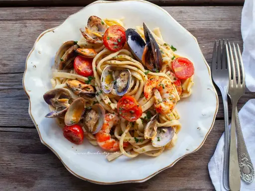 Un piatto invitante di scialatielli ai frutti di mare, con cozze, vongole, gamberi e pomodorini freschi, guarnito con prezzemolo.