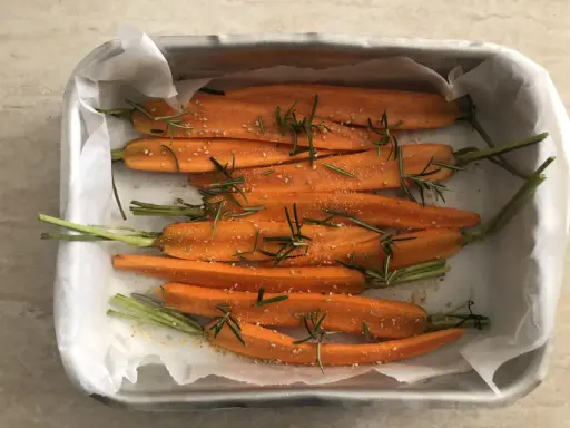 Carote al forno, condite con rosmarino e semi di sesamo, pronte per essere gustate.