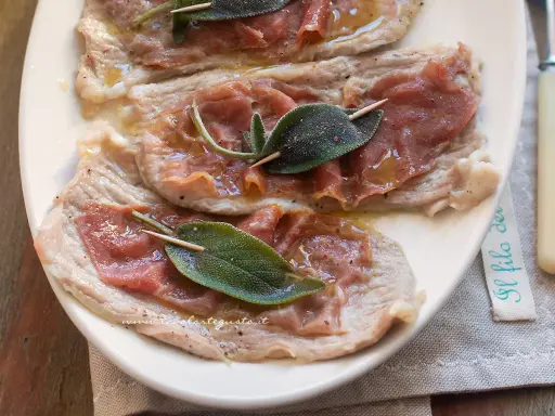 Saltimbocca alla romana: fettine di vitello con prosciutto crudo e salvia, condite con olio e pepe.