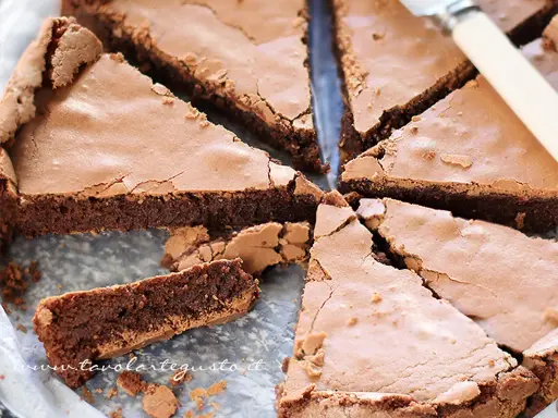 Una deliziosa torta al cioccolato, tagliata a fette triangolari, mostra la sua consistenza umida e ricca.