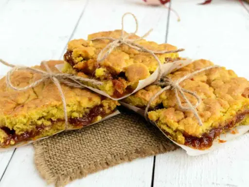 Tre deliziose fette di torta con marmellata, legate con spago e avvolte in carta da forno, pronte per essere gustate.