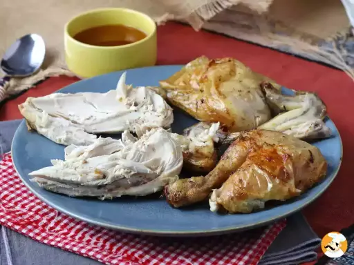 Piatto di petto di pollo arrosto succulento, tagliato a pezzi, con una ciotolina di salsa.