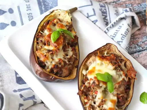 Melanzane ripiene al forno velocissime, con un saporito ripieno e formaggio filante, guarnite con basilico fresco.