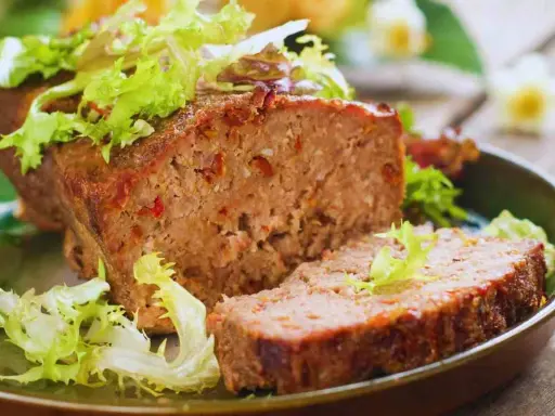 Un succulento polpettone al forno, tagliato a fette e guarnito con insalata fresca.