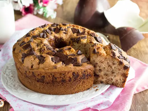 Ciambellone soffice con gocce di cioccolato, perfetto per la colazione di Pasqua, con uova di Pasqua sullo sfondo.