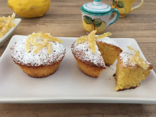 Deliziosi muffin caprese al limone, spolverati di zucchero a velo e decorati con scorzette candite.