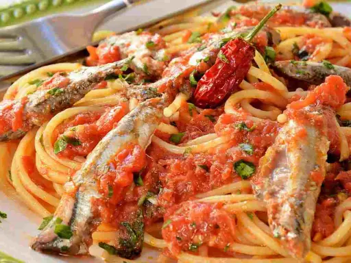Spaghetti con sugo di pomodoro, acciughe intere e un peperoncino rosso piccante. Un piatto di pasta semplice e saporito.