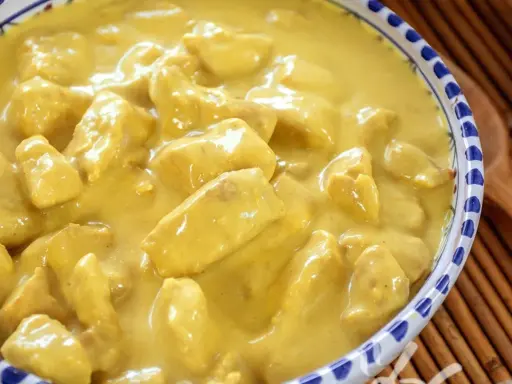 Un invitante pollo al curry con latte di cocco, cremoso e profumato, servito in una ciotola decorata.