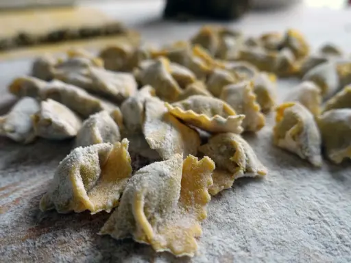 Un mucchio di ravioli del plin freschi, spolverati di farina, pronti per essere cucinati.