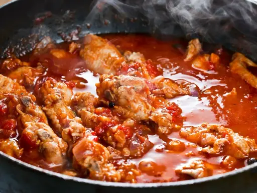 Succulenta carne alla pizzaiola che sobbolle in padella, sprigionando un profumo invitante. Pezzi di carne tenera immersi in un sugo rosso ricco di pomodoro e spezie.