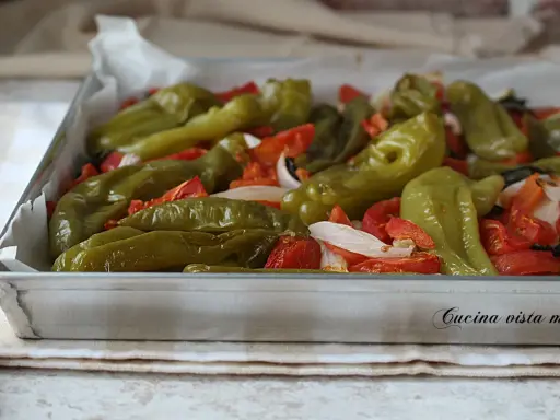 Friggitelli al forno con pomodori e cipolla, un contorno saporito e colorato, pronto per essere gustato.