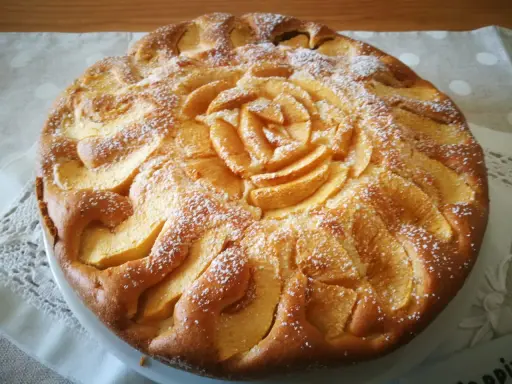 Una deliziosa torta di mele senza glutine, decorata con mele a forma di rosa e spolverata di zucchero a velo.
