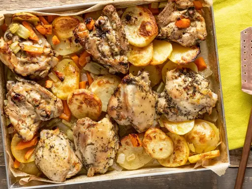 Sovracosce di pollo dorate al forno con patate, carote e sedano, pronte per essere servite.