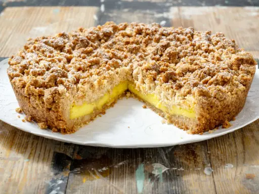 Sbriciolata alla crema con una crosta dorata e un ripieno giallo brillante, cosparsa di zucchero a velo.
