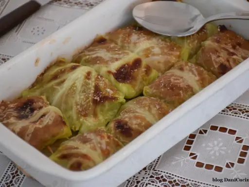 Involtini di verza con carne appena sfornati, dorati e spolverati di parmigiano, pronti per essere gustati.