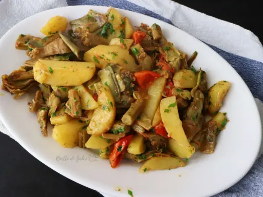 Deliziosi carciofi e patate in padella, un contorno saporito e colorato, arricchito da pomodorini e prezzemolo fresco.