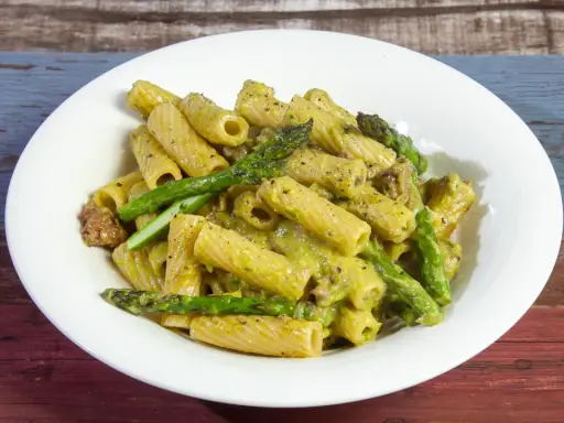 Piatto di pasta con asparagi e salsiccia, condita con una cremosa salsa verde.