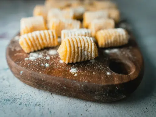 Gnocchi di patate fatti in casa, pronti per essere cucinati, spolverati di farina su un tagliere di legno.