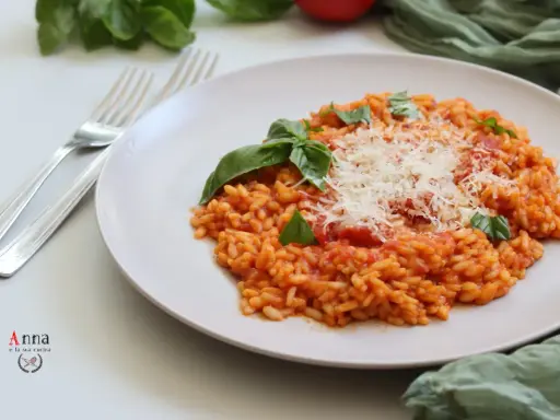 Un cremoso risotto al pomodoro, guarnito con basilico fresco e parmigiano grattugiato, pronto per essere gustato.