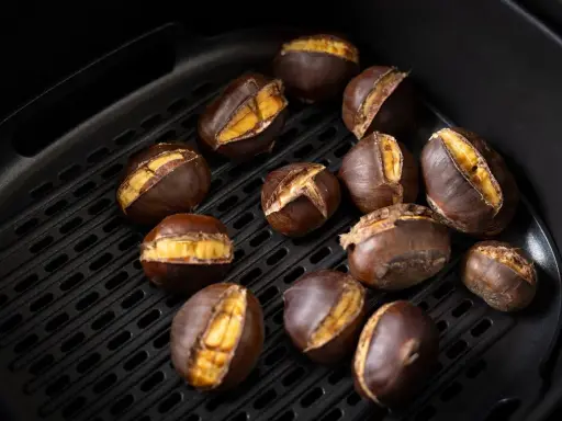 Castagne arrostite nella friggitrice ad aria, con la buccia aperta che rivela il loro interno dorato e invitante.