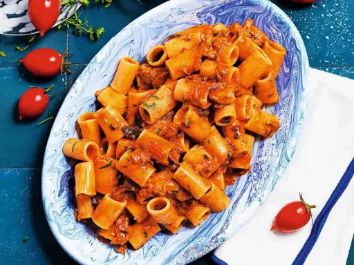 Rigatoni conditi con un sugo rosso saporito, ricco di tonno e erbe aromatiche. Un piatto di pasta al tonno invitante.