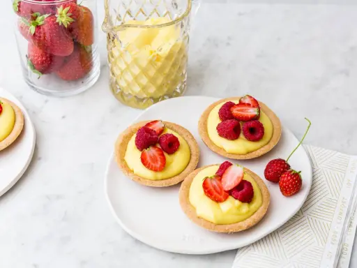 Deliziose tartellette alla frutta con crema pasticcera e frutti di bosco freschi, pronte per essere gustate.