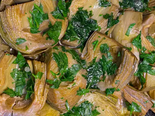 Deliziosi carciofi in padella, teneri e profumati, guarniti con prezzemolo fresco. Un piatto semplice e gustoso.