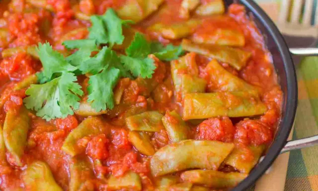 Taccole al pomodoro cotte in padella, guarnite con prezzemolo fresco. Un piatto semplice e gustoso.