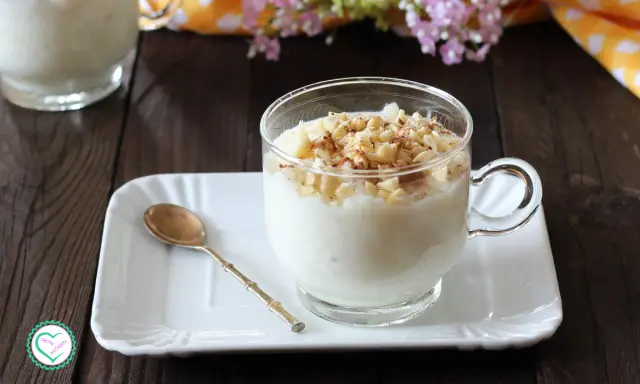 Una tazza di cremosa crema di riso, guarnita con mandorle tritate e cannella, pronta per essere gustata.
