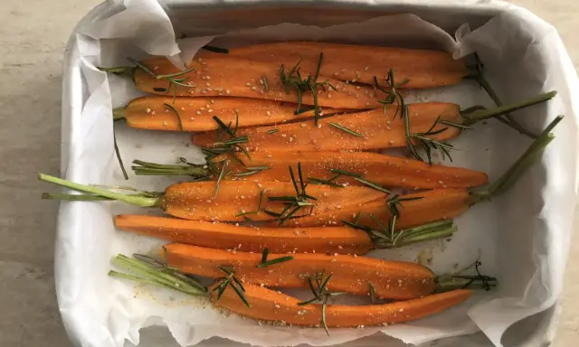 Carote al forno, condite con rosmarino e semi di sesamo, pronte per essere gustate.