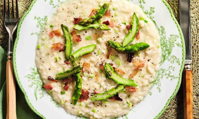 Un cremoso risotto asparagi e zafferano, guarnito con punte di asparagi freschi e cubetti croccanti di pancetta.