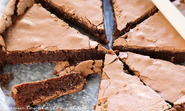 Una deliziosa torta al cioccolato, tagliata a fette triangolari, mostra la sua consistenza umida e ricca.