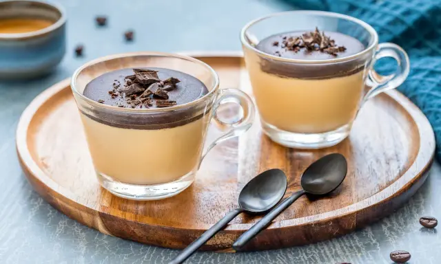 Delizioso semifreddo al caffè con copertura al cioccolato e scaglie croccanti, servito in coppette di vetro su un vassoio di legno.