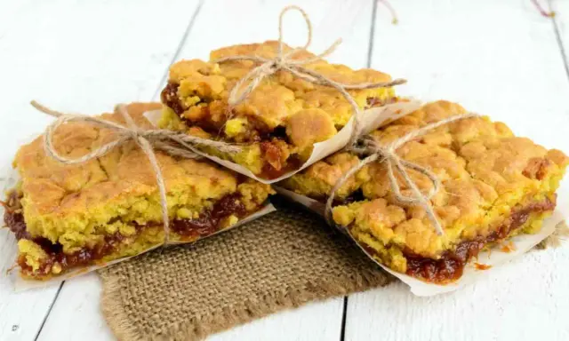 Tre deliziose fette di torta con marmellata, legate con spago e avvolte in carta da forno, pronte per essere gustate.