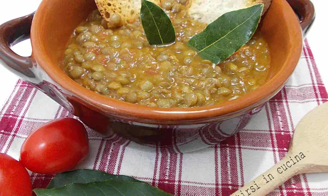 Un piatto fumante di lenticchie in umido, guarnito con crostini e foglie di alloro, pronto per essere gustato.