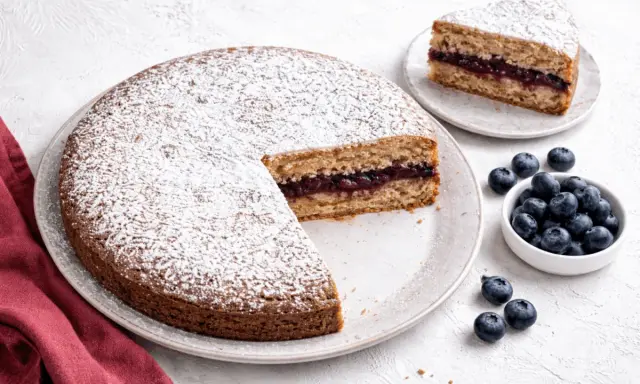Torta senza glutine con marmellata di frutti di bosco, spolverata di zucchero a velo, accompagnata da mirtilli freschi.
