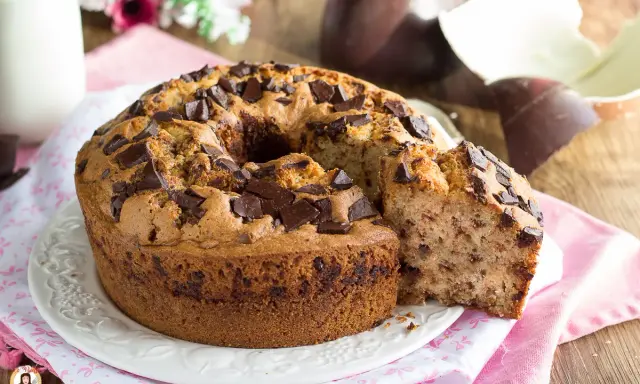 Ciambellone soffice con gocce di cioccolato, perfetto per la colazione di Pasqua, con uova di Pasqua sullo sfondo.