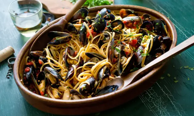 Un invitante piatto di spaghetti con le cozze, condito con pomodoro e prezzemolo, pronto per essere gustato.