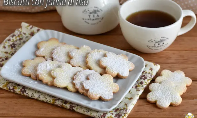 Biscotti con farina di riso a forma di fiore, spolverati di zucchero a velo, serviti con una tazza di tè.