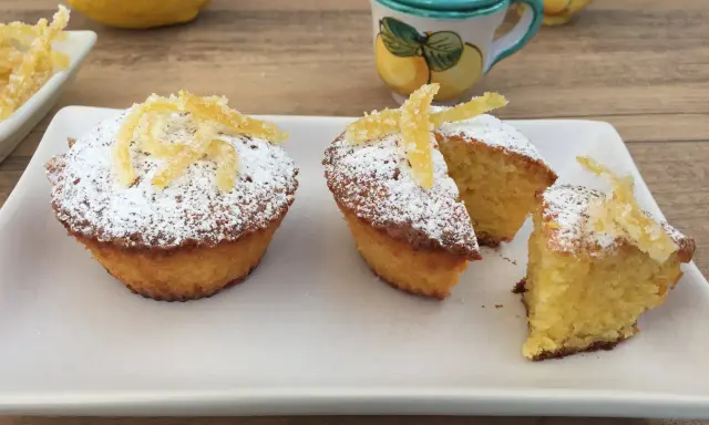 Deliziosi muffin caprese al limone, spolverati di zucchero a velo e decorati con scorzette candite.