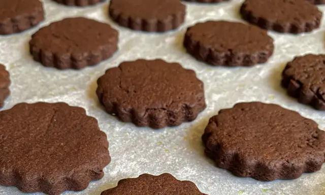 Deliziosi biscotti senza burro al cacao, con bordo ondulato, disposti su una teglia.