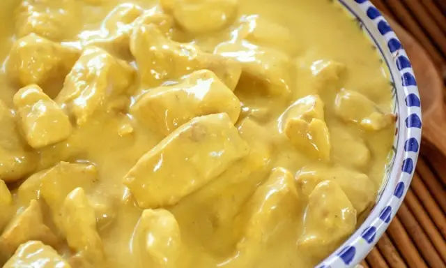 Un invitante pollo al curry con latte di cocco, cremoso e profumato, servito in una ciotola decorata.