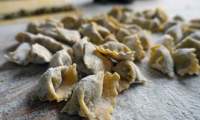 Un mucchio di ravioli del plin freschi, spolverati di farina, pronti per essere cucinati.