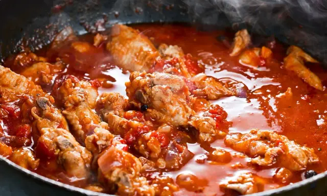 Succulenta carne alla pizzaiola che sobbolle in padella, sprigionando un profumo invitante. Pezzi di carne tenera immersi in un sugo rosso ricco di pomodoro e spezie.